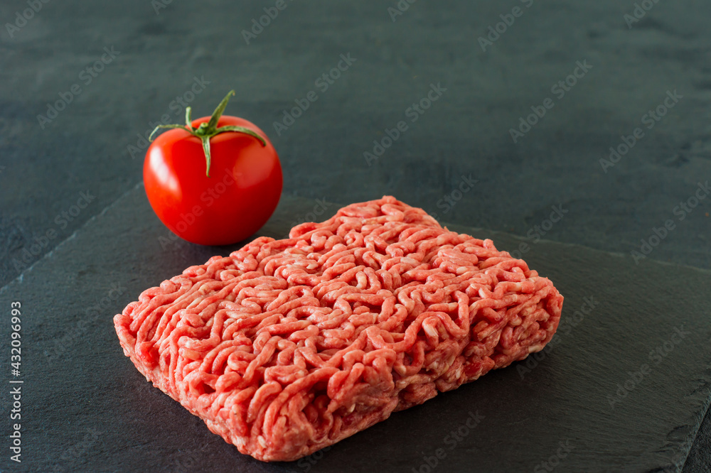 Raw minced beef meat on a slate with tomato. Raw minced beef meat on a slate with tomato.