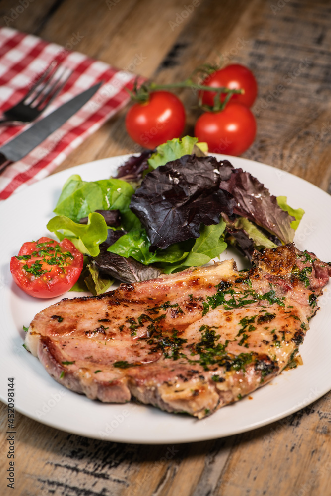 Recipe for grilled pork chop, maple syrup and fresh cilantro marinade, parsley, garlic, served with a salad.