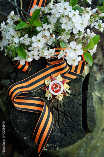 Victory Day holiday, symbol memory of war, may 9, 1945. old soviet Military order of Second World war, st.George ribbon, spring flowers on dark wooden background.  photo