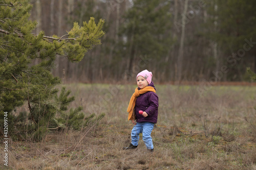 a small child with a toy in his hands stands near a tree and dances