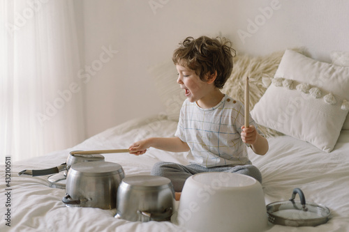 Fotografia Cute young boy using wooden sticks to bang saucepans that are set up like a drumset