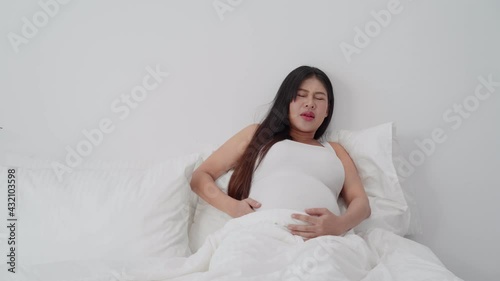 pregnant Asian woman suffering pain. beautiful pregnant woman touching her tummy
