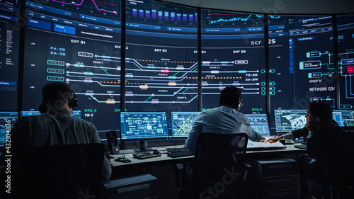 Professional IT Technical Support Specialists and Software Programmer Working on Computers in Monitoring Control Room with Digital Screens with Server Data, Blockchain Network and Surveillance Maps. 