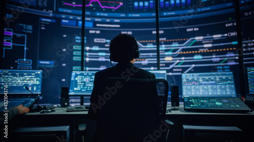 Professional IT Technical Support Specialists and Software Programmer Working on Computers in Monitoring Control Room with Digital Screens with Server Data, Blockchain Network and Surveillance Maps.  © Gorodenkoff