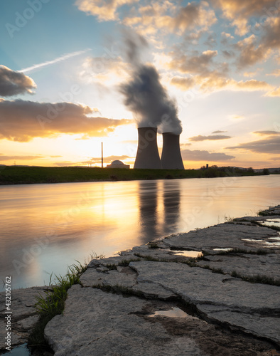 Nuclear power plant against sky by the river at sunset