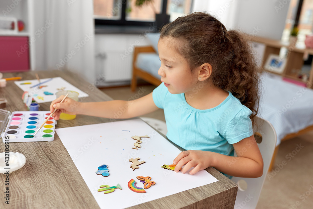 childhood, hobby and leisure concept - little girl with brush painting wooden chipboard items at home childhood, hobby and leisure concept - little girl with brush painting wooden chipboard items at home