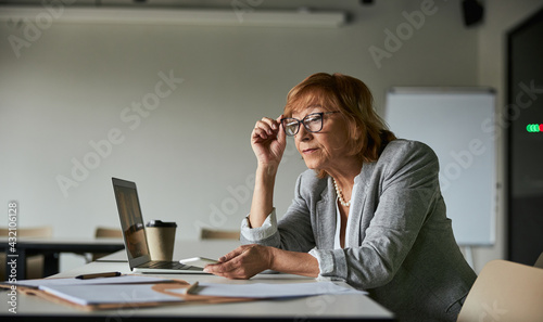 Fotografía Female adjusting her glasses while reading paper records