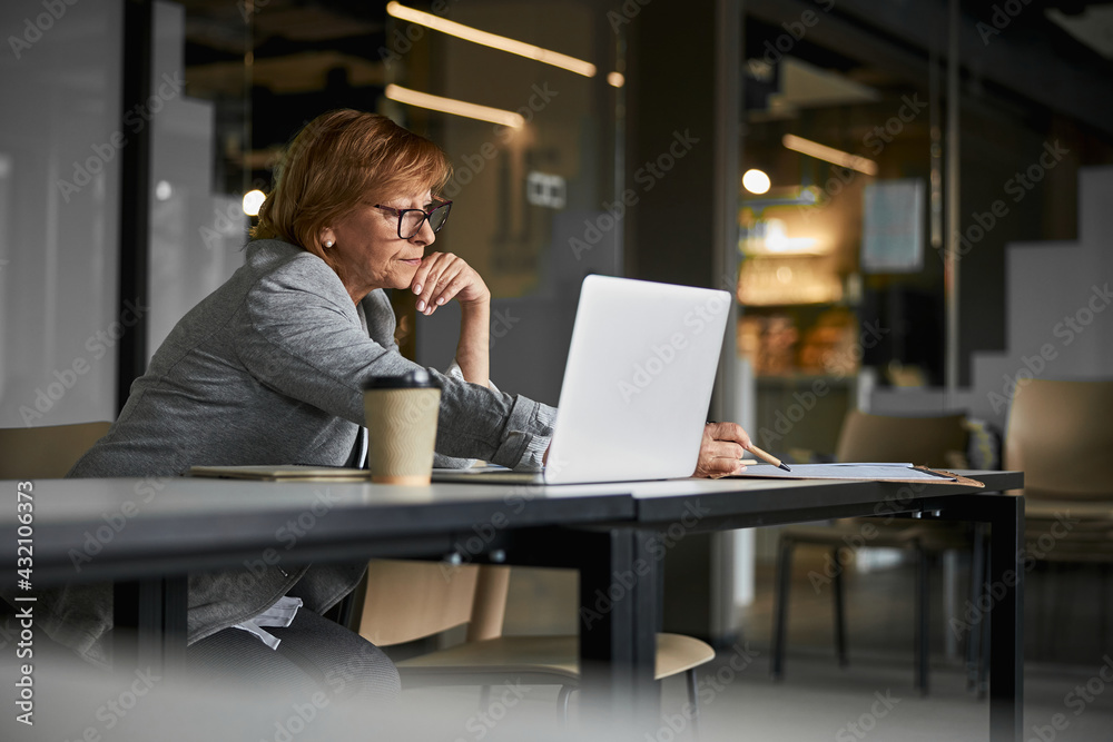 Diligent female CEO reaching out to write notes on paper Diligent female CEO reaching out to write notes on paper