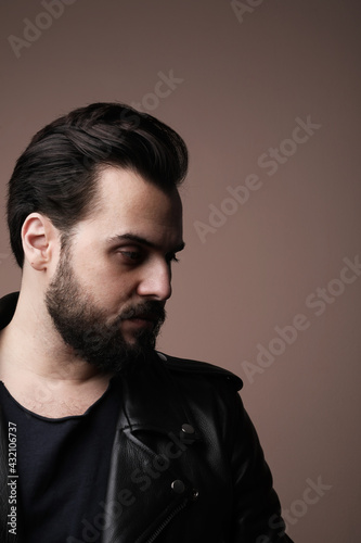 Side portrait of bearded brutal man. Posing on the white wall.