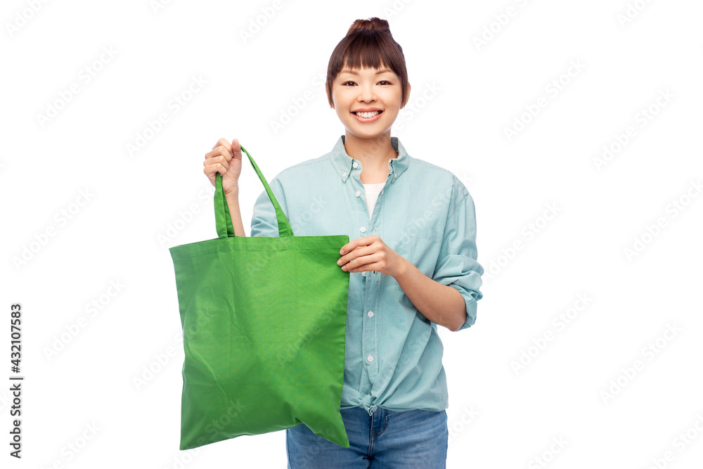 sustainability and people concept - happy smiling young asian woman in turquoise shirt and jeans with green reusable canvas bag for food shopping over white background sustainability and people concept - happy smiling young asian woman in turquoise shirt and jeans with green reusable canvas bag for food shopping over white background