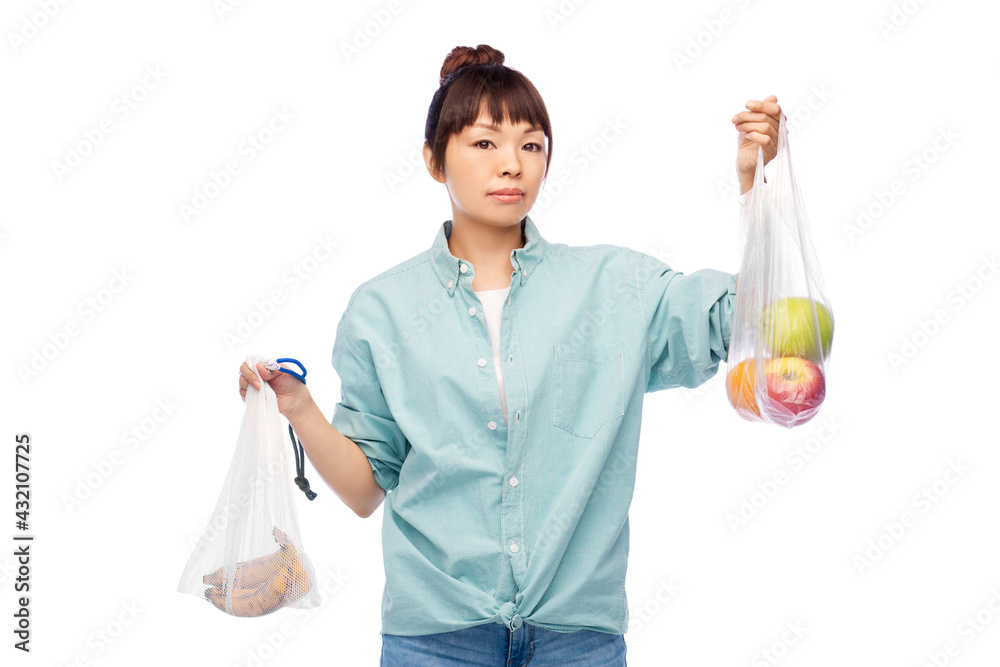 sustainability, eco living and people concept - portrait of young asian woman in turquoise shirt and jeans holding reusable bag with bananas and plastic bag with apples over white background sustainability, eco living and people concept - portrait of young asian woman in turquoise shirt and jeans holding reusable bag with bananas and plastic bag with apples over white background