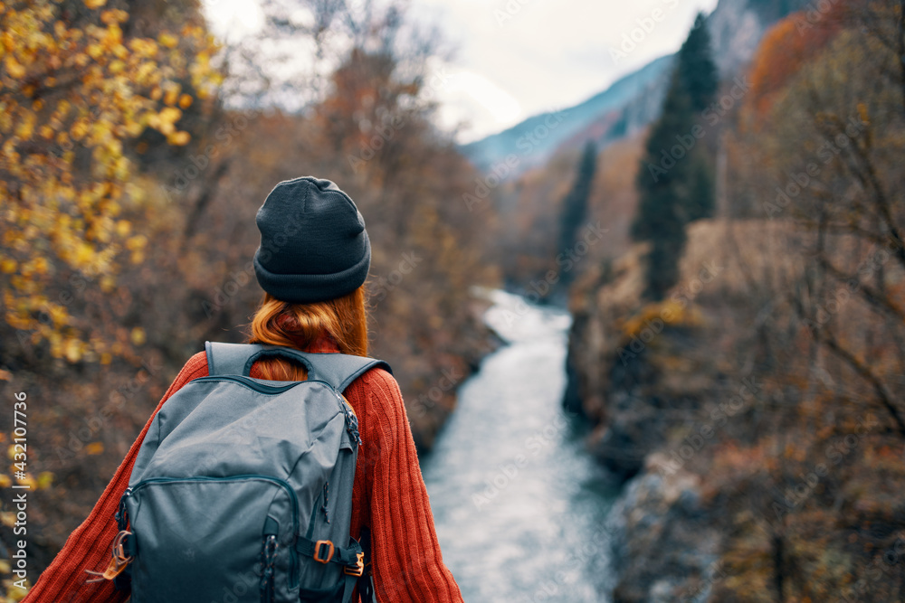 woman hiker with a backpack on her back near a mountain river in nature, back view woman hiker with a backpack on her back near a mountain river in nature, back view