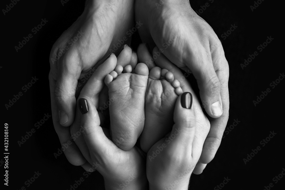Children's feet in hold hands of mother and father. Mother, father and newborn Child. Happy Family people concept. Black and white. Children's feet in hold hands of mother and father. Mother, father and newborn Child. Happy Family people concept. Black and white.