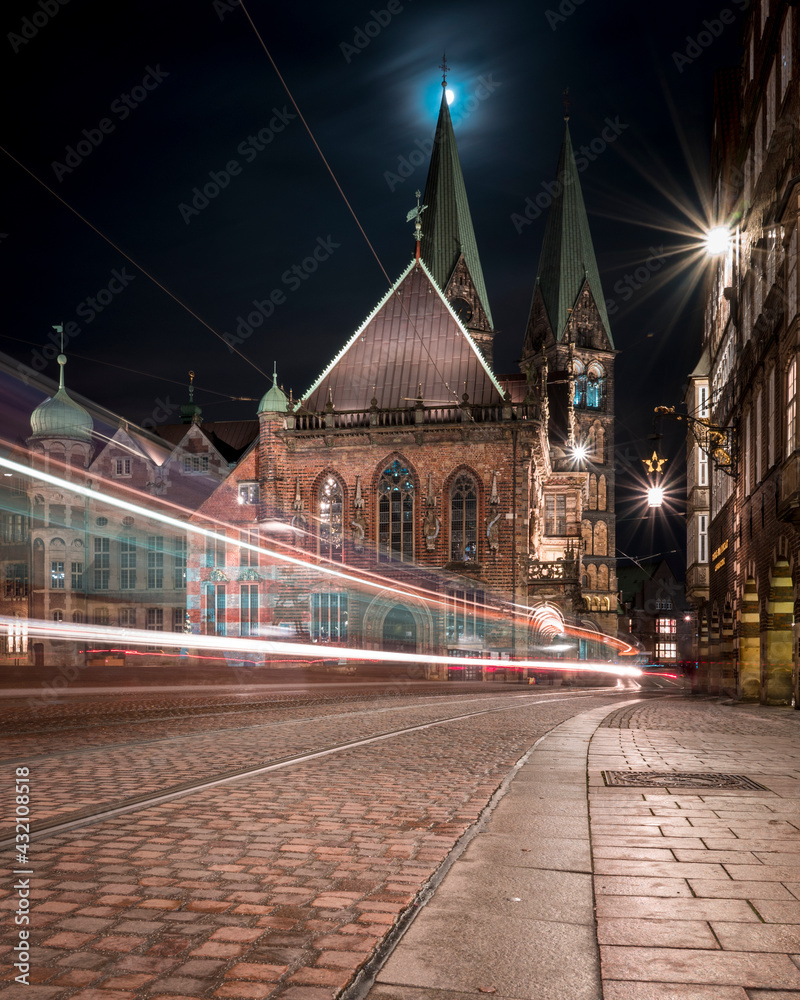 Fototapeta premium The Bremer Dom at night with the moon and a tram