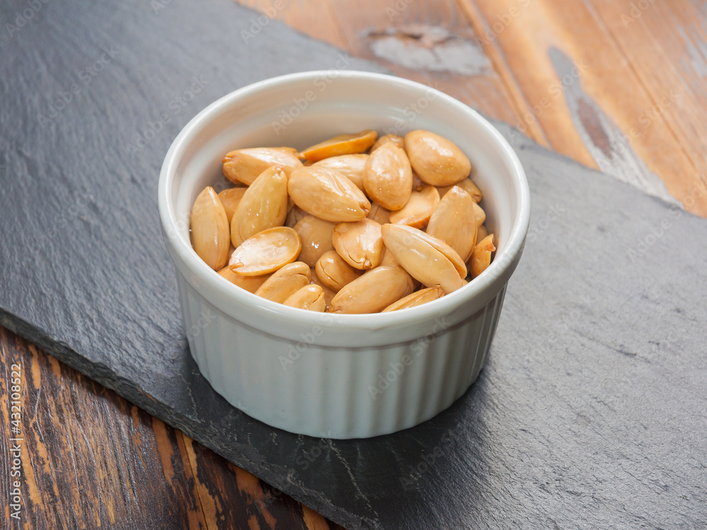 peeled almonds fried with salt in a small Cup on a black stone Board peeled almonds fried with salt in a small Cup on a black stone Board