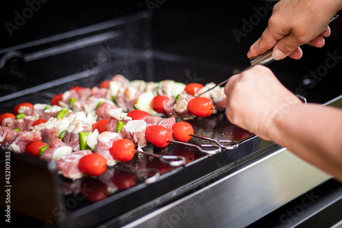 grillades de Brochettes de poulet et tomate sur une plancha qui cuisent 