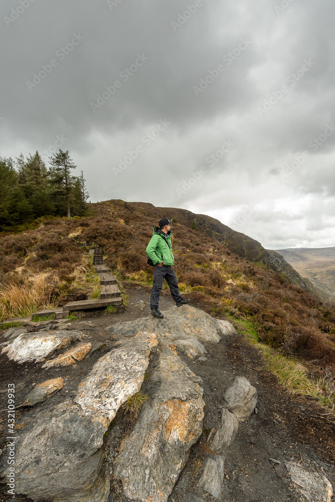 A Man in green jacket standing on top of hill admiring the scenery in the Mountains of Wicklow Ireland