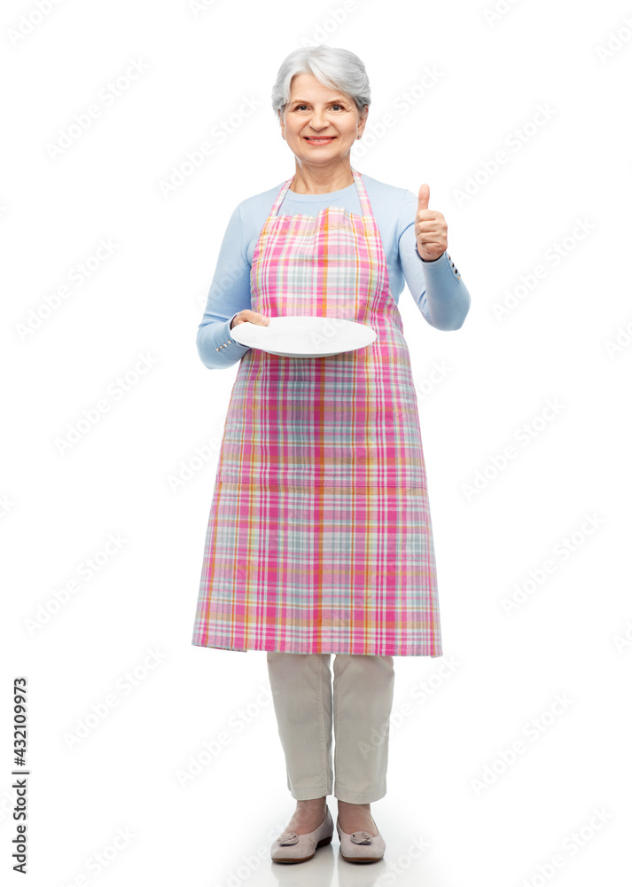 cooking, culinary and old people concept - smiling senior woman in kitchen apron with empty plate showing thumbs up over white background cooking, culinary and old people concept - smiling senior woman in kitchen apron with empty plate showing thumbs up over white background