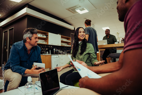 Fotografía Diverse group of people having meeting in office lounge discussing new project w
