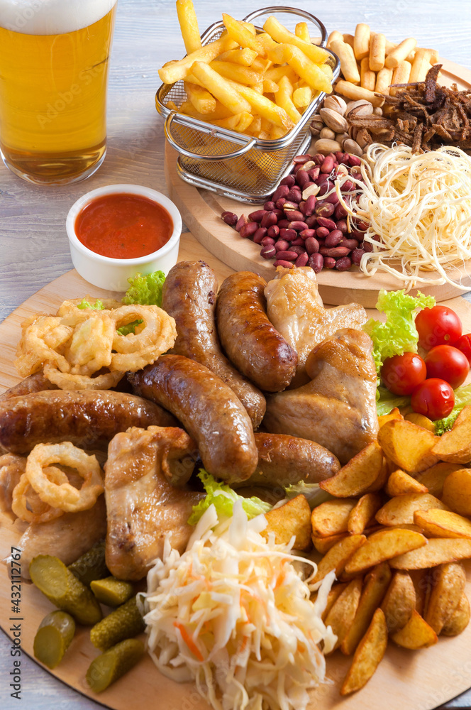 assorted beer snacks: chicken wings, grilled sausages, potatoes, nuts, cheese, croutons