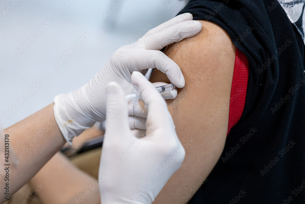 Obraz premium Close up doctor, nurse holding syringe making covid-19 vaccination injection dose in shoulder patient. Corona virus treatment side effect, close up view. Flu Vaccination Injection on Arm.