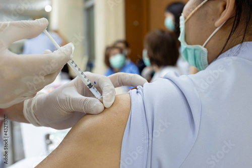 Close up doctor, nurse holding syringe making covid-19 vaccination injection dose in shoulder patient. Corona virus treatment side effect, close up view. Flu Vaccination Injection on Arm.
