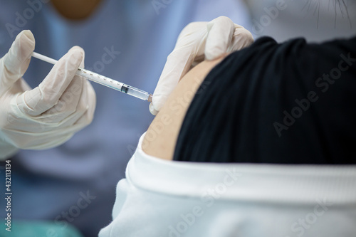 Close up doctor, nurse holding syringe making covid-19 vaccination injection dose in shoulder patient. Corona virus treatment side effect, close up view. Flu Vaccination Injection on Arm.