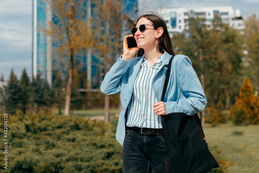 A cheerful young business woman is talking with someone on her phone in park being positive A cheerful young business woman is talking with someone on her phone in park being positive