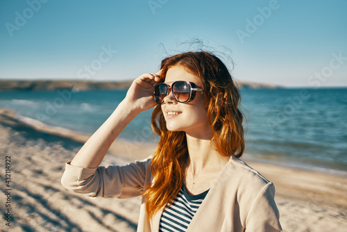 happy woman on the beach near the sea in the mountains glasses on the face red hair model landscape