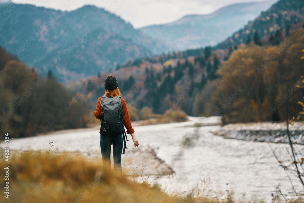 woman on vacation with a backpack on the river bank in the mountains