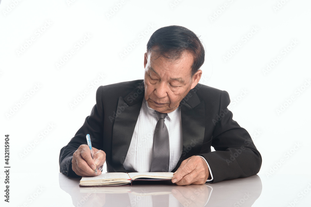 Close up older asian business man putting signature on legal documents. Senior man freelancer writing details on book on desk in living room. Close up older asian business man putting signature on legal documents. Senior man freelancer writing details on book on desk in living room.