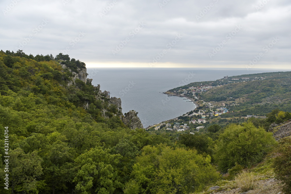 Sevastopol, Crimea - 10.15.2015 : Rocky mountains with different vegetation on the background of the Black Sea and city buildings on the shore Sevastopol, Crimea - 10.15.2015 : Rocky mountains with different vegetation on the background of the Black Sea and city buildings on the shore