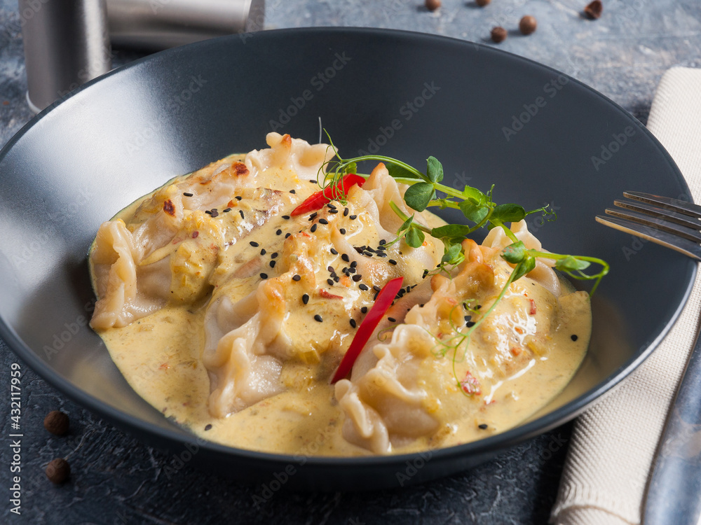 gyoza dumplings in curry sauce decorated with micro greenery in a dark plate gyoza dumplings in curry sauce decorated with micro greenery in a dark plate