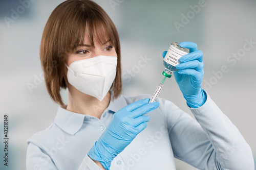 female doctor or nurse is pulling up a syringe with coronavirus vaccination serum photo