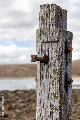 A close up of a jetty post from the myponga jetty ruins with the hills selectively blurred on the fleurieu peninsula south australia on may 3rd 2021