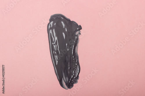 The texture of a black clay mask or cream. Cosmetic smear on pink background