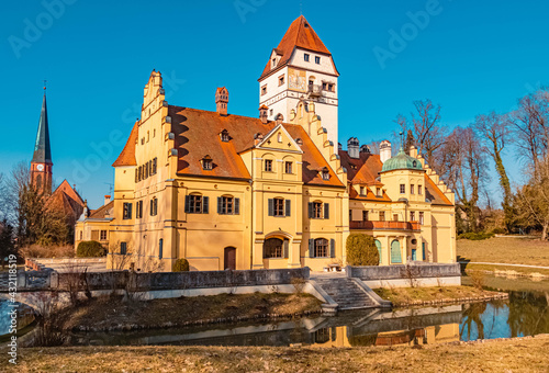 Beautiful winter view on a sunny day with a water castle and reflections at Schoenau, Bavaria, Germany