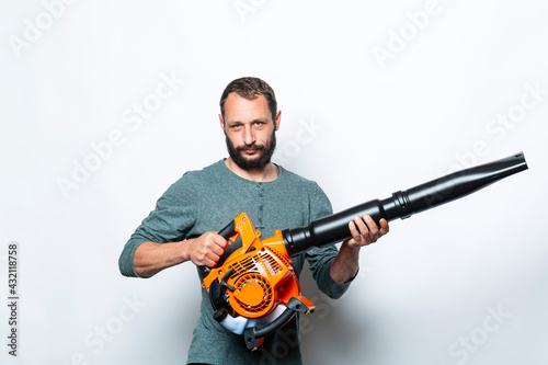 I'm ready to go and start up my leaf blower. Studio portrait of Serious man holds in Hands blower machine. Handsome Caucasian Worker looking at camera. People, lifestyle and technology concept