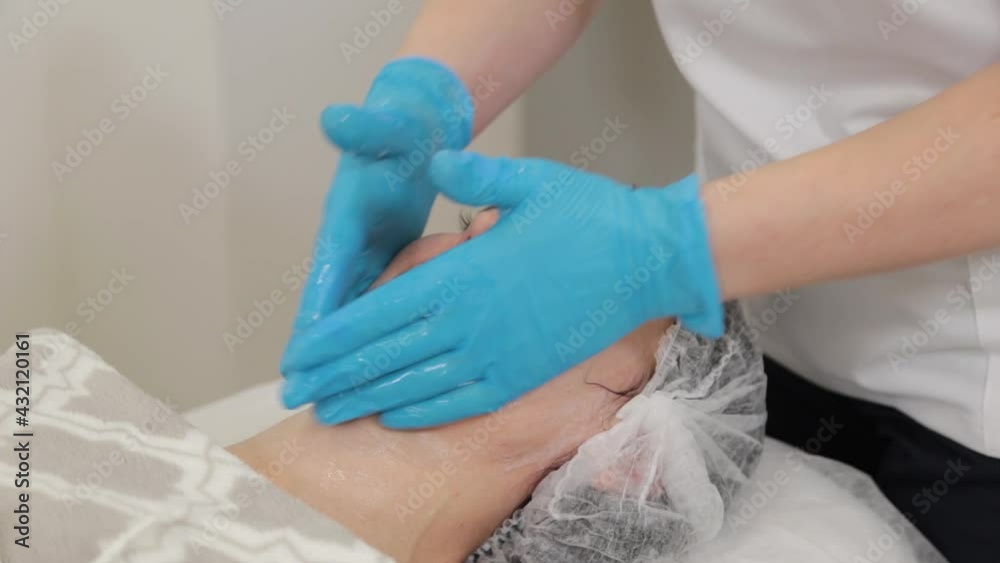 Woman beautician massages the face of a client. Woman beautician massages the face of a client.