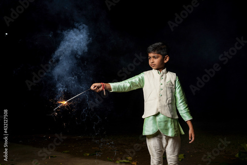 Cute Indian child celebrating Diwali festival with cracker and sparkle © PRASANNAPIX