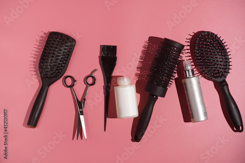 Hair brushes, scissors and tools for hair dresser on pink background in hard light