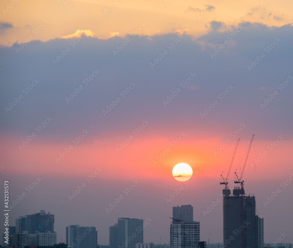 High rise buildings with construction site in sunset.