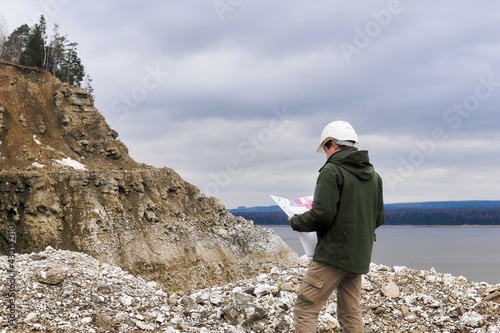 geologist with a map on a steep river bank