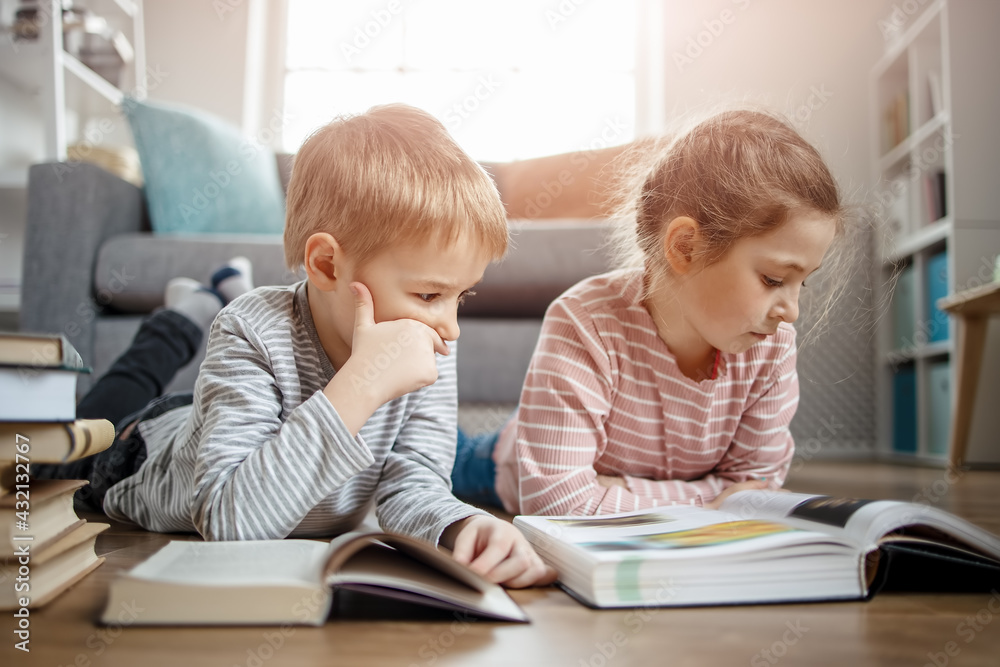 Cute children lying down on the floor and reading books Cute children lying down on the floor and reading books
