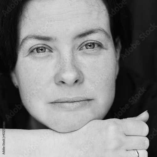 Close-up black and white portrait of a woman. A slight smile and shining eyes on a woman's face.