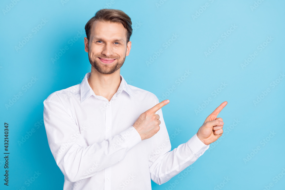 Photo of happy charming young man point index fingers empty space good mood isolated on blue color background Photo of happy charming young man point index fingers empty space good mood isolated on blue color background