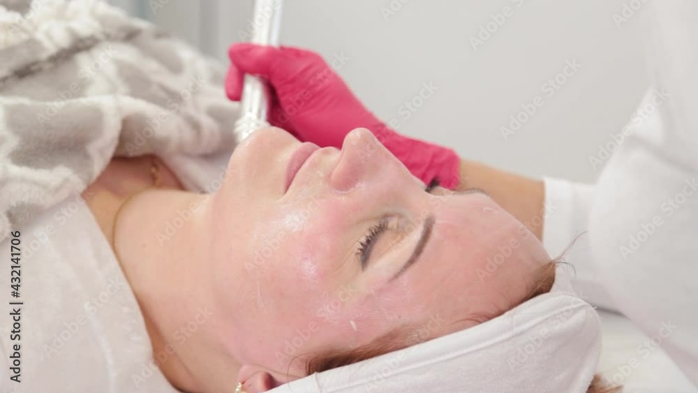 Woman cosmetologist treats her face with a device in the cosmetology office. Woman cosmetologist treats her face with a device in the cosmetology office.