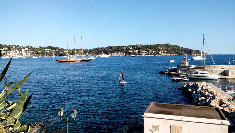 Obraz premium Yachts and boats in the harbor. Beautiful panoramic landscape of Villefranche-sur-mer on a sunny day. A wonderful trip to the Cote d'Azur in France. Scenic harbour view of the city of the sea country.