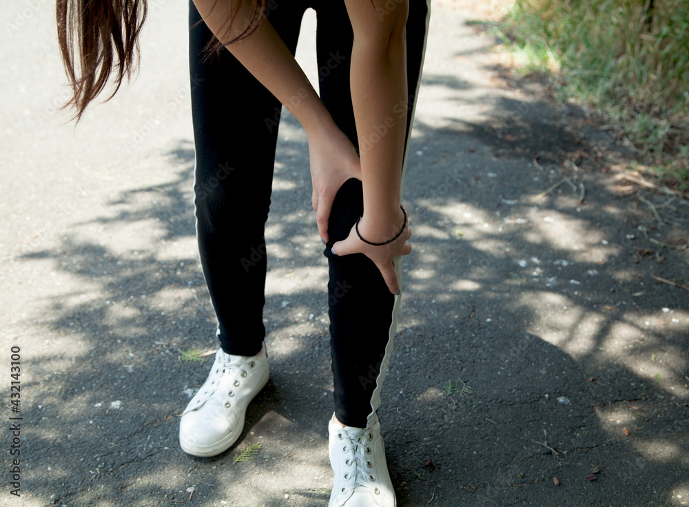 Woman's leg hurts while running in the park.