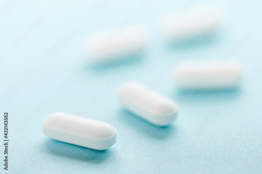 White pills isolated on blue background White pills isolated on blue background